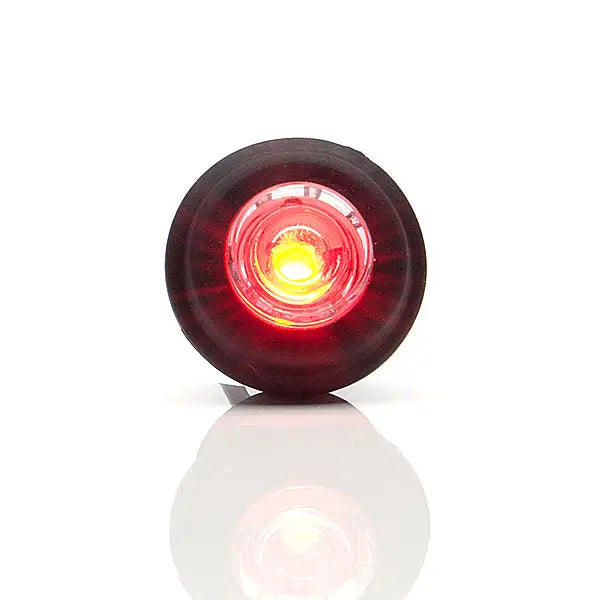 Pyöreä punaisena loistava LED-äärivalo mustalla kumikehyksellä, joka heijastuu valkoisesta alustasta.