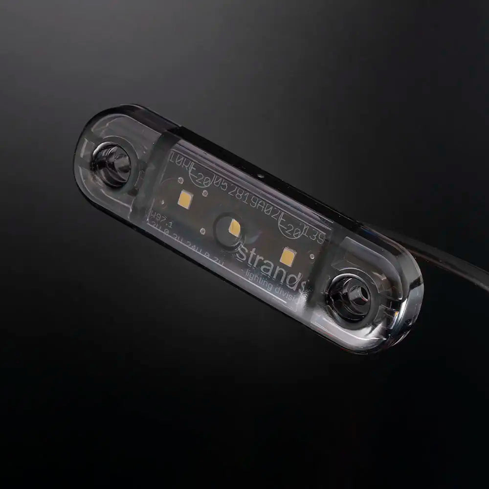 Kytkemätön, kapea ja tummalinssinen LED-äärivalo kuvattuna viistosti tummaa, lähes mustaa taustaa vasten.