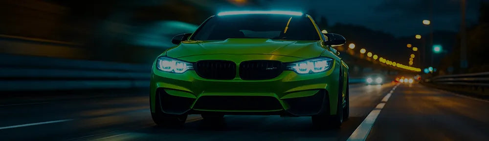 Vihreä bmw ajaa pimeällä moottoritiellä missä katolla tehokas lisävalopaneeli.
